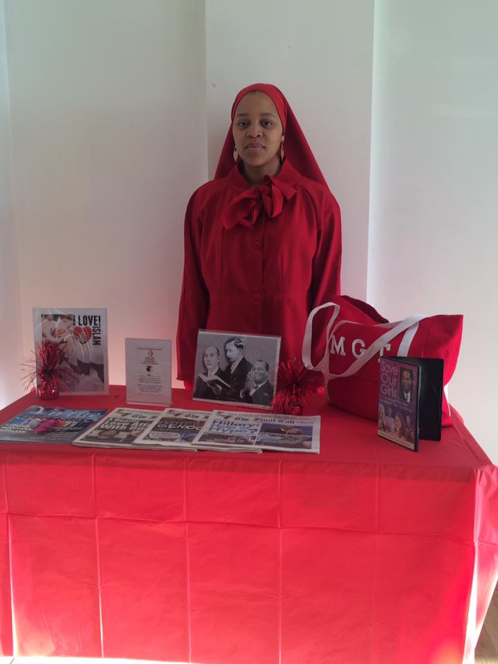 muslim woman standing by table with books on display